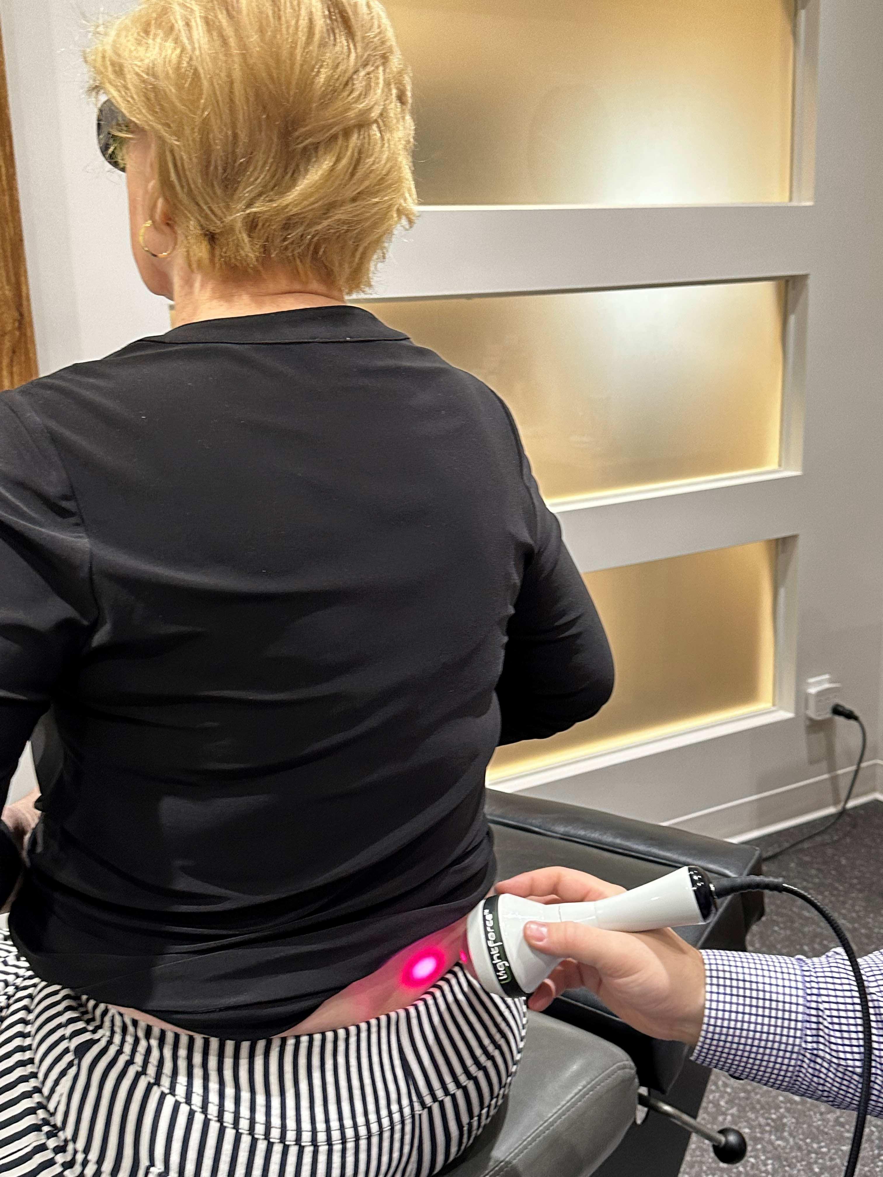Application de laser dans le bas du dos d'un patient par un docteur dans le cadre d'un traitement dans une clinique.