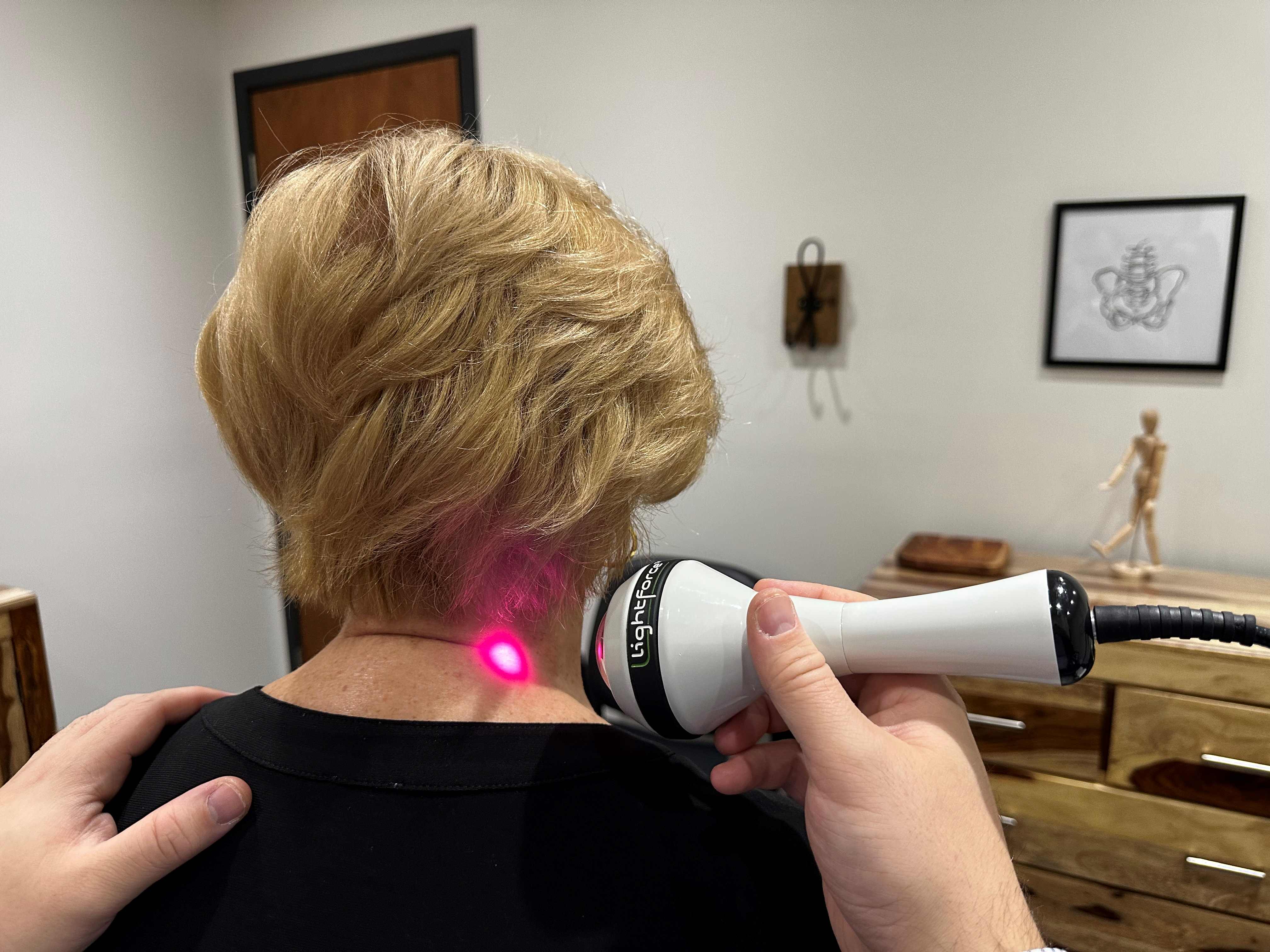 Application de laser sur le cou d'une patiente par un docteur dans le cadre d'un traitement dans une clinique.