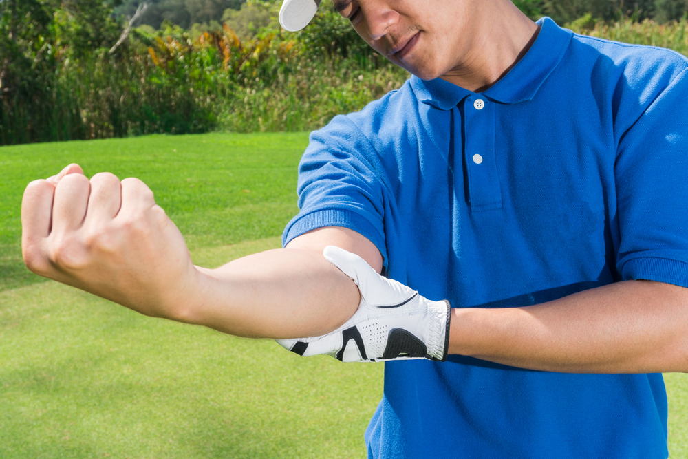 Joueur de golf sur un terrain de golf qui tient son coude visiblement en douleur