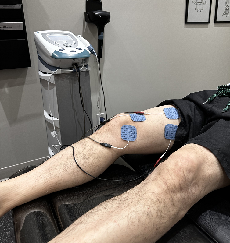 Homme allongé sur le dos avec des électrodes placées sur sa cuisse droite dans le cadre d'un traitement dans une clinique