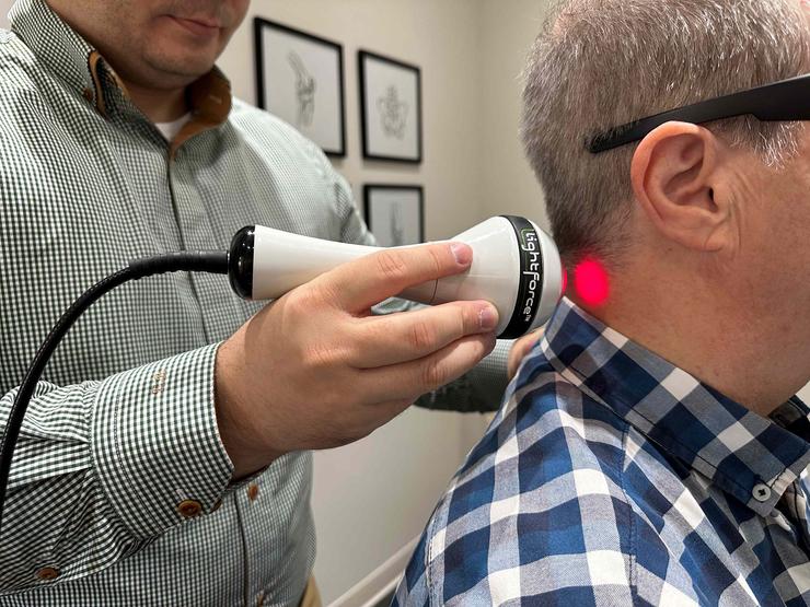 Application de laser dans le cou d'un patient par un docteur dans le cadre d'un traitement dans une clinique.